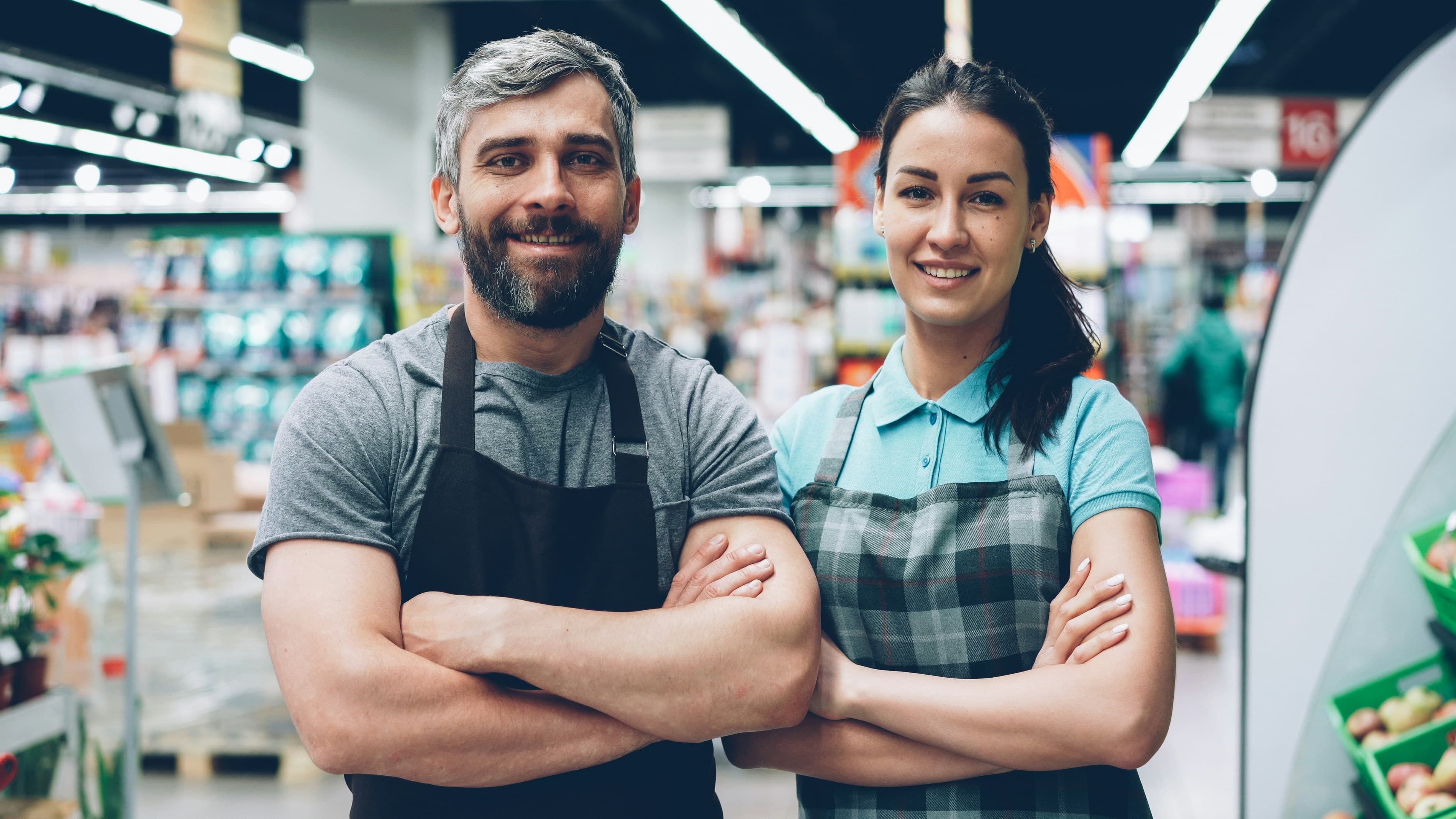 Due addetti di un supermercato sorridono con il grembiule
